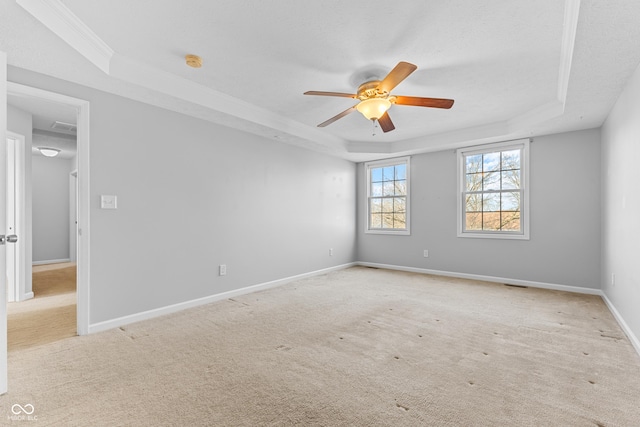 carpeted spare room featuring ceiling fan, a raised ceiling, and crown molding