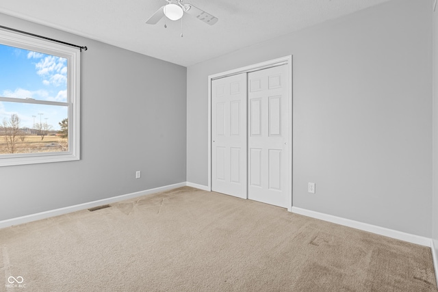 unfurnished bedroom with carpet floors, a closet, and ceiling fan