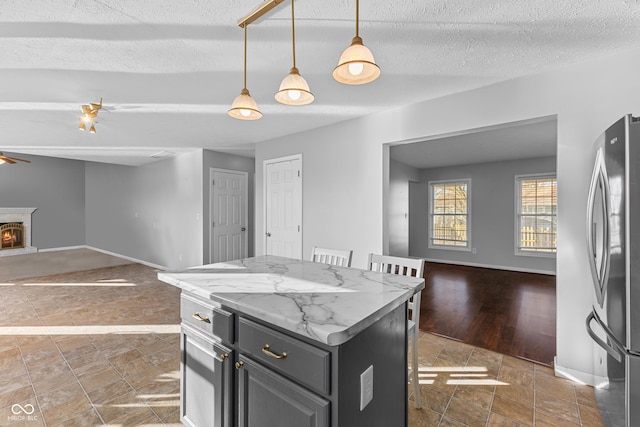 kitchen with a kitchen breakfast bar, decorative light fixtures, stainless steel refrigerator, and a kitchen island