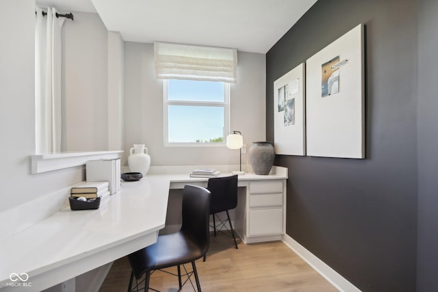 home office with light hardwood / wood-style flooring and built in desk