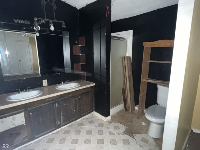 bathroom featuring toilet, a shower with shower door, and vanity