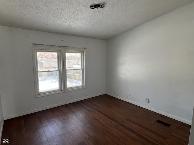 unfurnished room with a textured ceiling and dark hardwood / wood-style floors