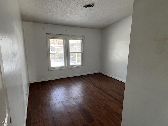 empty room featuring dark wood-type flooring and a textured ceiling