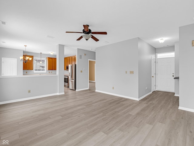 unfurnished living room featuring light hardwood / wood-style flooring and ceiling fan with notable chandelier