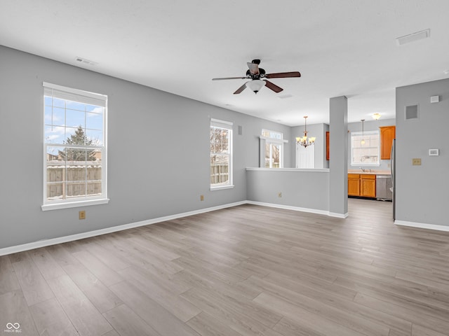 unfurnished living room with ceiling fan with notable chandelier, light hardwood / wood-style floors, a healthy amount of sunlight, and sink