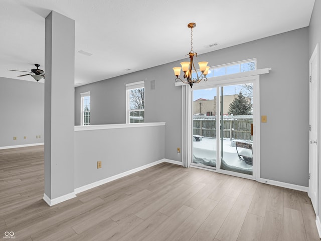 unfurnished dining area with ceiling fan with notable chandelier and light wood-type flooring