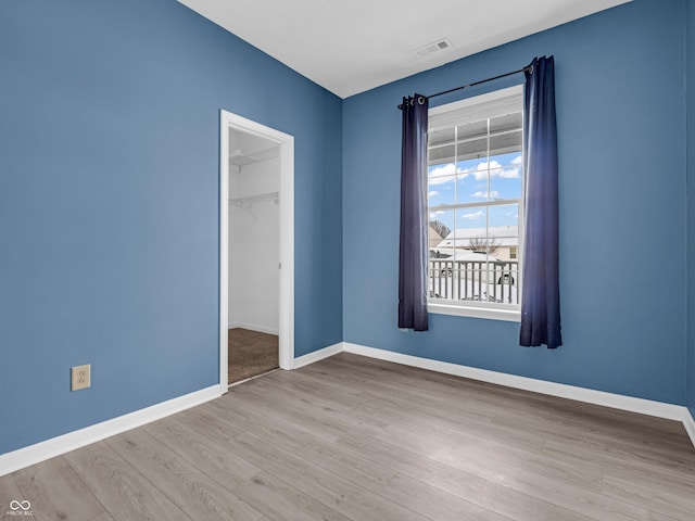 unfurnished bedroom with a spacious closet, light wood-type flooring, and a closet