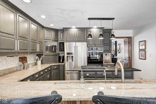 kitchen with light stone counters, hanging light fixtures, decorative backsplash, and stainless steel appliances