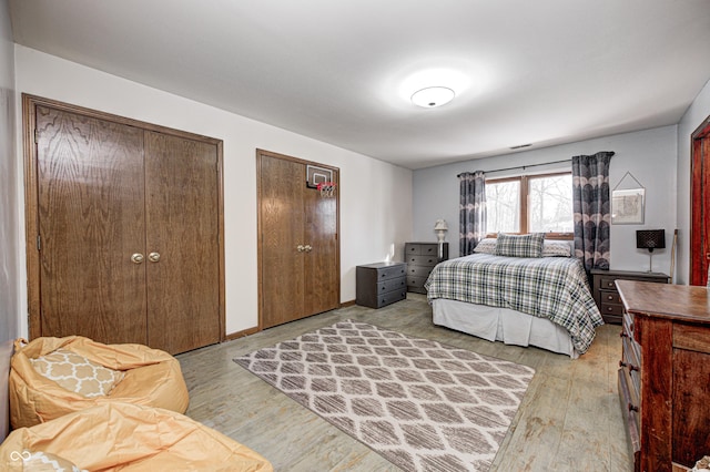 bedroom with multiple closets and light hardwood / wood-style floors