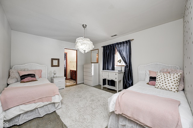 bedroom with a notable chandelier, connected bathroom, and hardwood / wood-style flooring