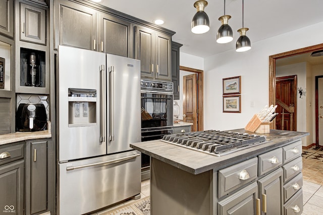 kitchen featuring stainless steel appliances, gray cabinetry, light tile patterned flooring, hanging light fixtures, and a center island