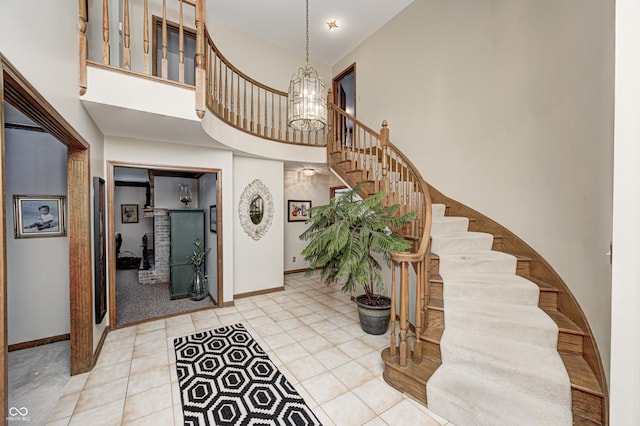 tiled entrance foyer featuring a towering ceiling and a chandelier