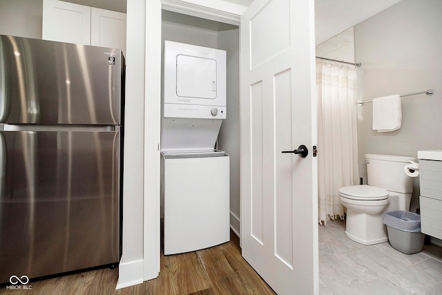 clothes washing area featuring stacked washer and dryer and light hardwood / wood-style flooring