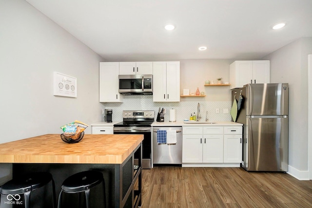 kitchen featuring wood counters, stainless steel appliances, white cabinets, and sink