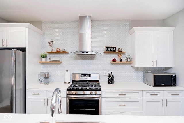 kitchen featuring backsplash, white cabinets, wall chimney range hood, and appliances with stainless steel finishes