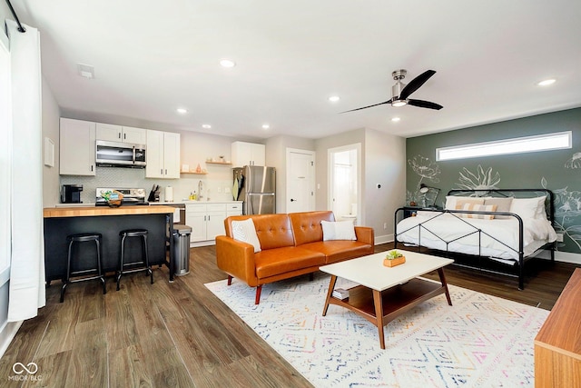 living room featuring wood-type flooring, ceiling fan, and sink