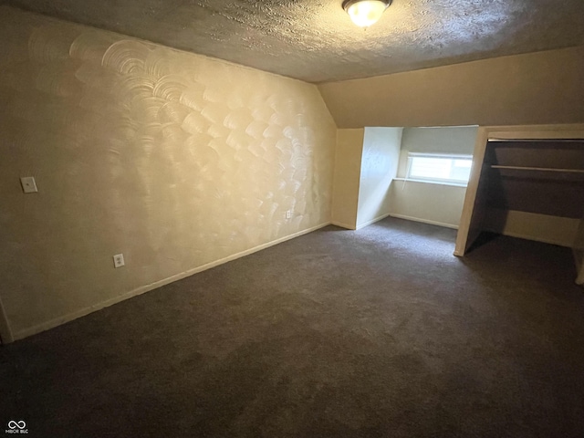 bonus room featuring dark colored carpet, a textured ceiling, and vaulted ceiling