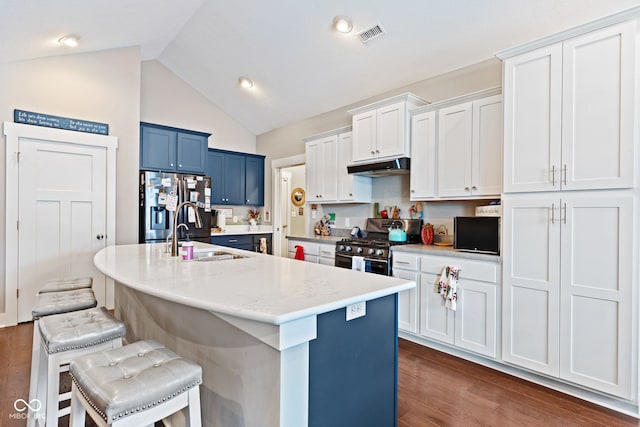 kitchen featuring appliances with stainless steel finishes, a kitchen breakfast bar, sink, lofted ceiling, and an island with sink