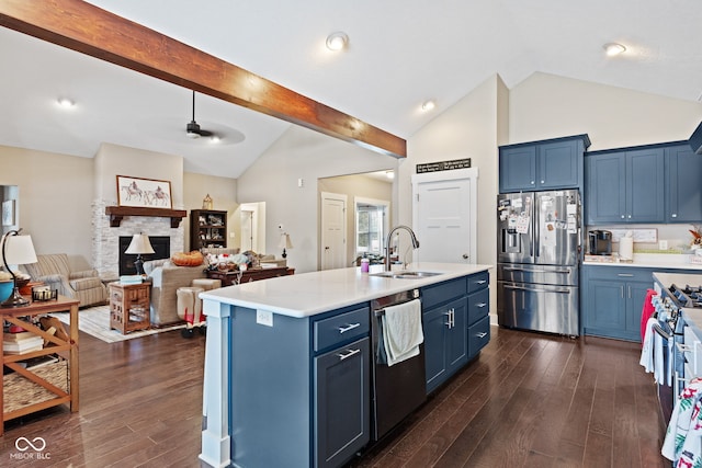 kitchen with a kitchen island with sink, a fireplace, stainless steel appliances, and blue cabinets