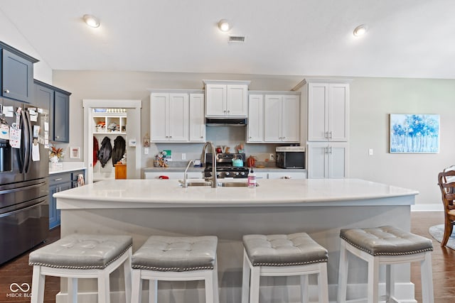 kitchen featuring dark wood-type flooring, a kitchen breakfast bar, sink, an island with sink, and stainless steel fridge with ice dispenser