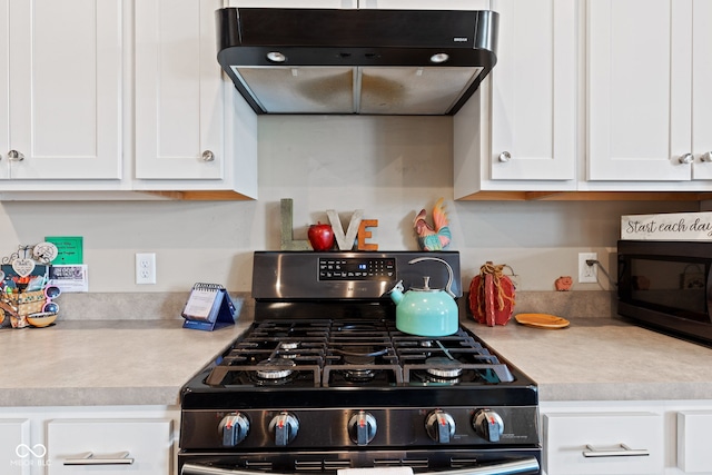 kitchen featuring ventilation hood, white cabinetry, and range