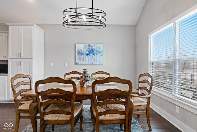 dining room featuring a notable chandelier, dark wood-type flooring, and vaulted ceiling