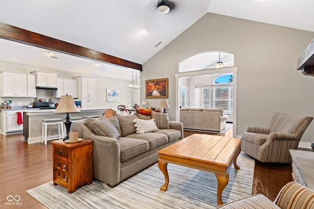 living room with ceiling fan, lofted ceiling with beams, and light wood-type flooring