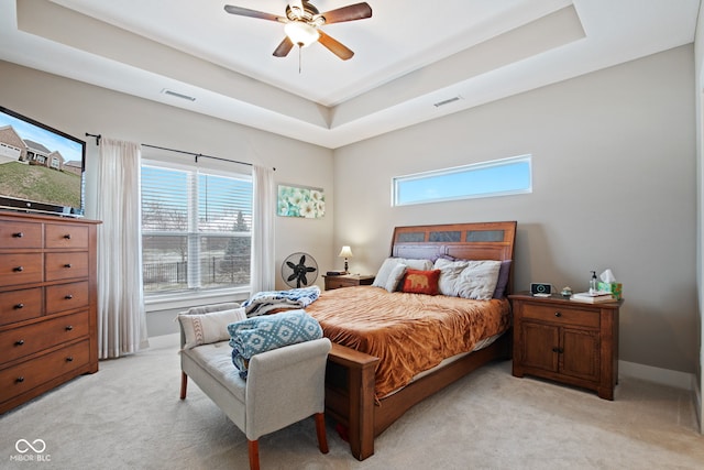 bedroom featuring ceiling fan, a raised ceiling, and light carpet