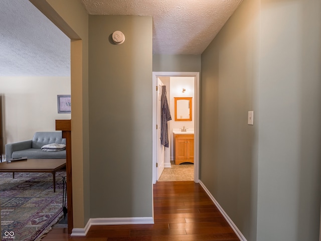 hallway featuring hardwood / wood-style floors, sink, and a textured ceiling