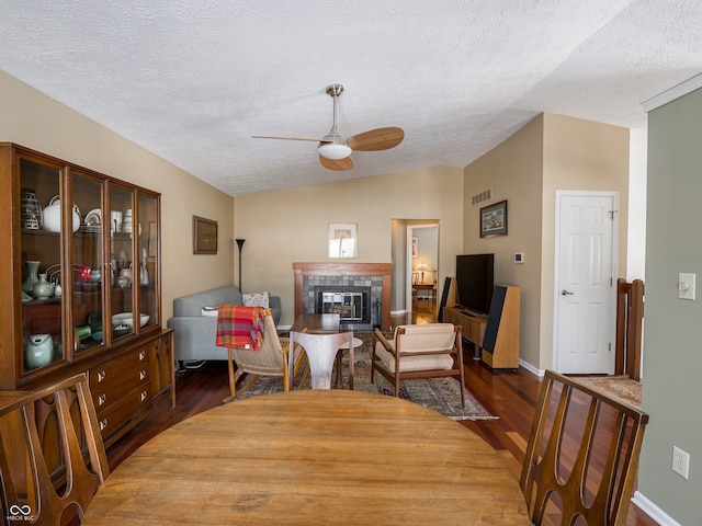 dining area featuring a textured ceiling, ceiling fan, dark wood-type flooring, and vaulted ceiling