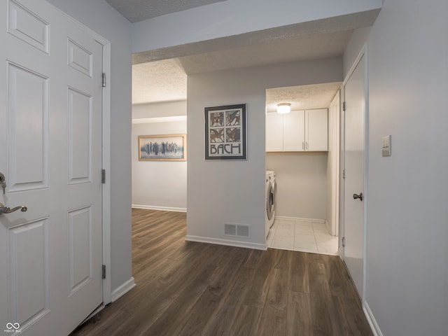 hall with washer and dryer, dark hardwood / wood-style floors, and a textured ceiling