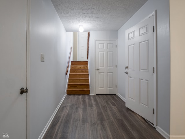 corridor featuring a textured ceiling and dark hardwood / wood-style flooring