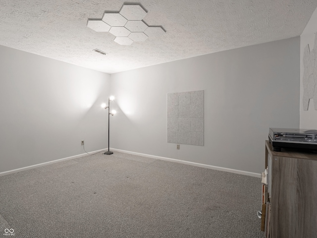 empty room with carpet floors and a textured ceiling