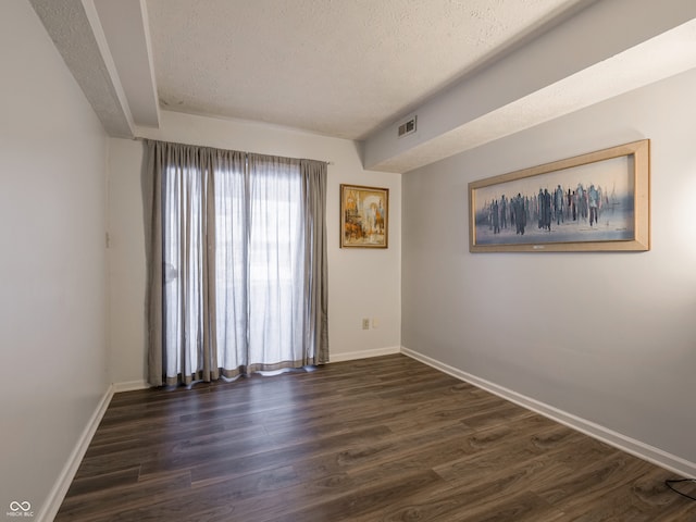 unfurnished room featuring a textured ceiling and dark wood-type flooring