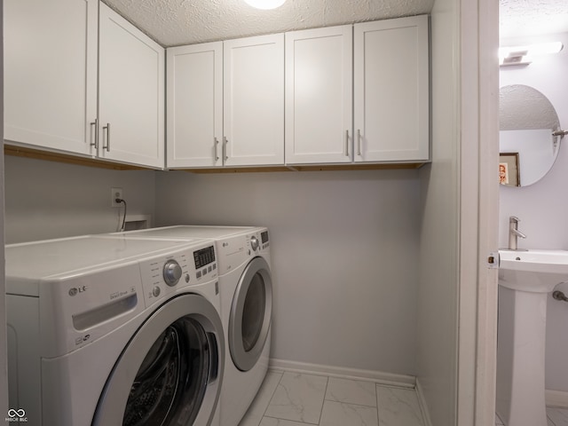 laundry room featuring separate washer and dryer, sink, cabinets, and a textured ceiling