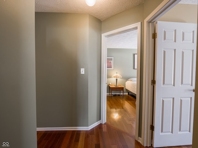 hall with a textured ceiling and dark wood-type flooring