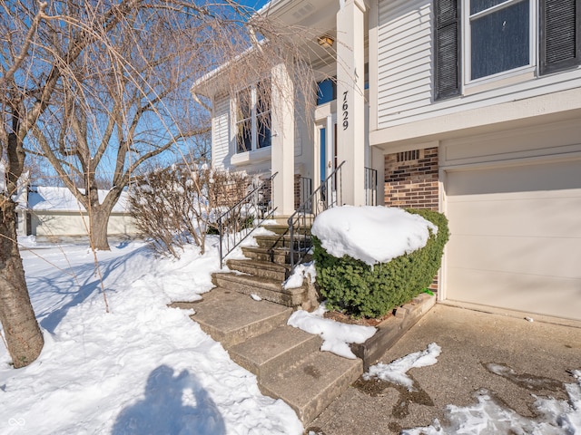 snow covered property entrance with a garage