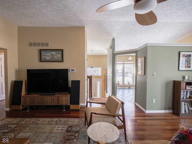 living room with a textured ceiling, dark hardwood / wood-style floors, and ceiling fan with notable chandelier