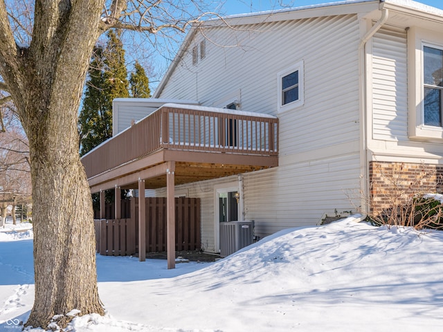 snow covered house with a deck and central air condition unit