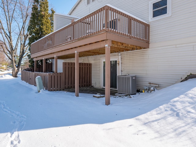 snow covered rear of property featuring a deck and central air condition unit