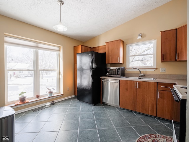 kitchen featuring sink, pendant lighting, a textured ceiling, dark tile patterned flooring, and appliances with stainless steel finishes