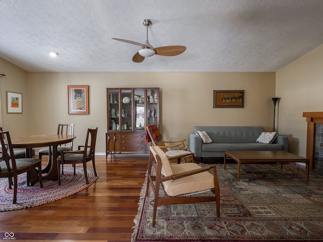 living room with ceiling fan, dark hardwood / wood-style flooring, and a textured ceiling