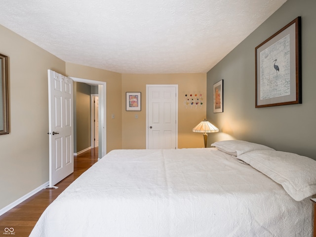 bedroom with a textured ceiling and dark hardwood / wood-style flooring