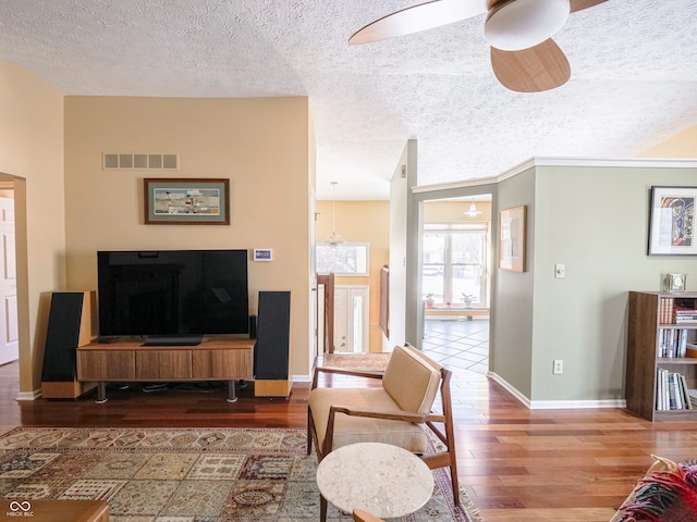 living room with visible vents, baseboards, ceiling fan, wood finished floors, and a textured ceiling