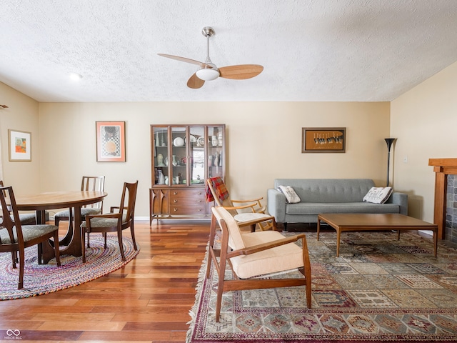 living room featuring a ceiling fan, wood finished floors, and a textured ceiling