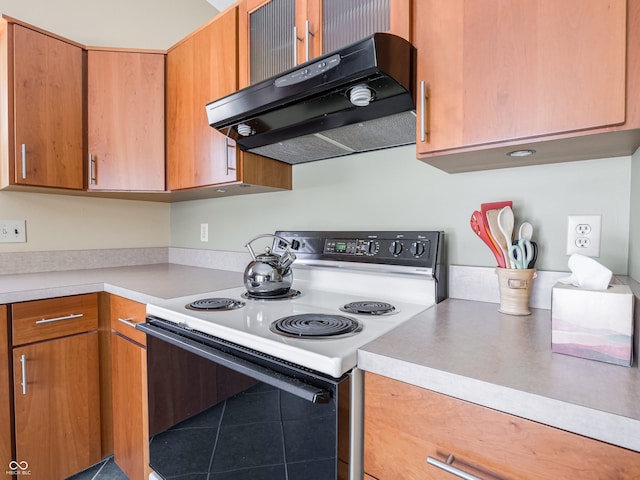 kitchen with under cabinet range hood, brown cabinetry, light countertops, and electric stove