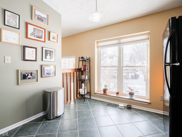 interior space with visible vents, a textured ceiling, baseboards, and dark tile patterned flooring