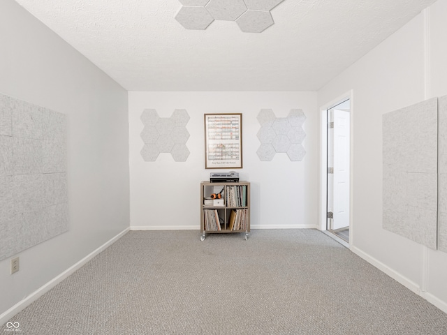 unfurnished room featuring a textured ceiling, baseboards, and carpet floors