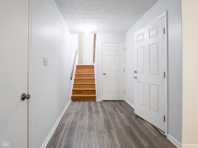 hall featuring dark wood-type flooring, stairway, baseboards, and a textured ceiling