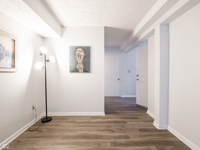 hall featuring a textured ceiling, baseboards, and wood finished floors